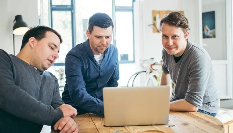 Paul, Michi und Nils im Austausch. Sie sitzen vor einem Laptop.