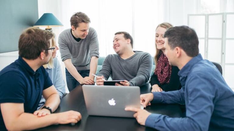 Das Hansolu-Team sitzt am Meetingtisch. Paul hat ein Tablet und Michi einen Laptop.