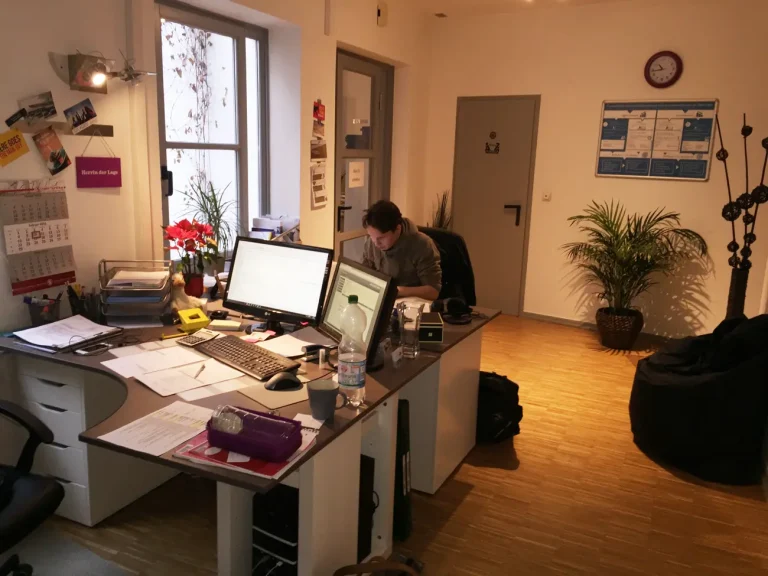 Nils in der Spätschicht. Er sitzt an seinem Schreibtisch und arbeitet an einem Laptop.