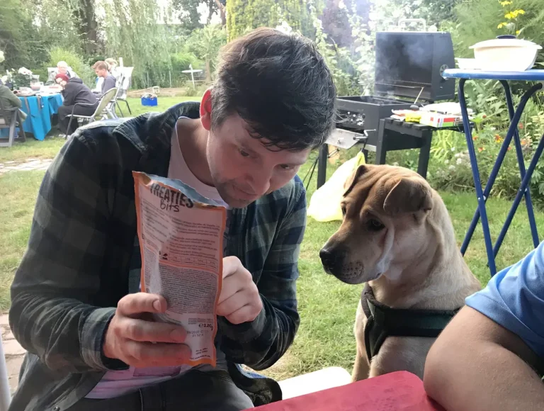 Michi und Charly auf der Hansolu-Gartenparty. Michi zeigt Charly (unser Bürohund) eine Packung mit Hundefutter.