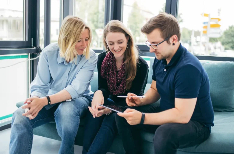 Teamarbeit: Website in der mobilen Darstellung testen. Andrea, Rebecca und Fabian schauen auf ein Tablet.