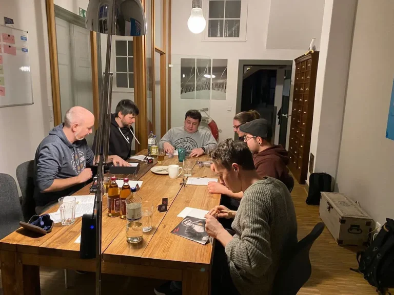Unser Krimidinner. Das Hansolu-Team sitzt abends im Meetingraum und spielt ein Krimispiel.