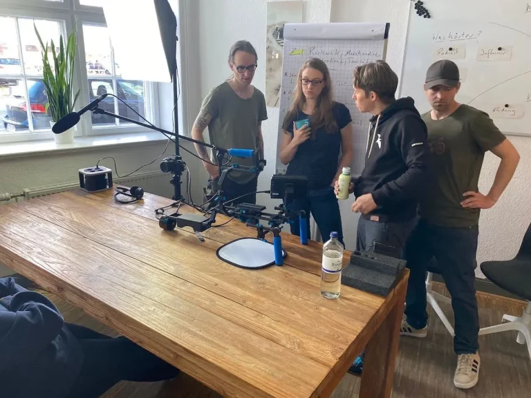 Fotoshooting. Rebecca, Nils und Michi besprechen schauen sie mit dem Fotografen Alex die Bilder an.