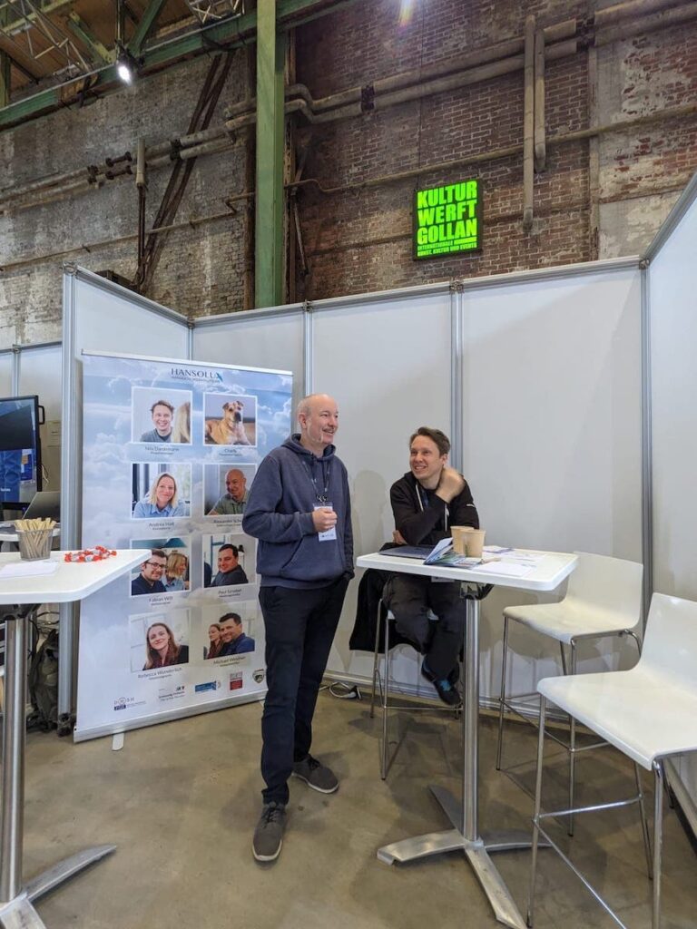 Unser Stand auf der IT for Business. Nils und Alex befinden sich am Hansolu-Stand und sprechen miteinander.