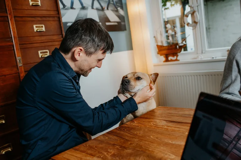 Michi krault Charlie, unserem Bürohund, den Hals, Beide befinded sich im Meetingraum am Teakholztisch.